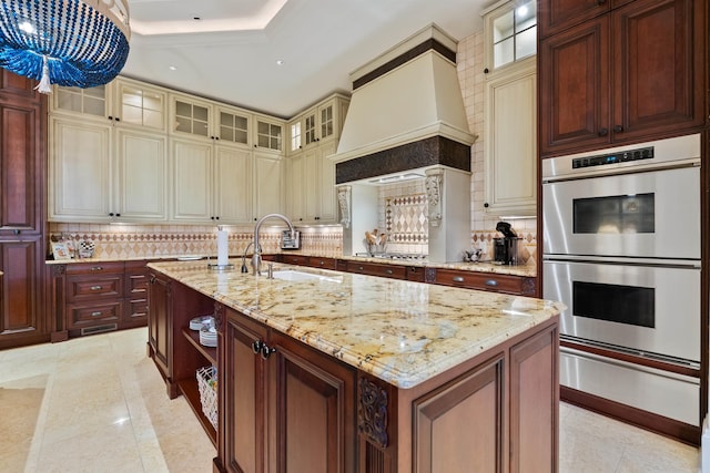 kitchen with a warming drawer, stainless steel appliances, custom range hood, backsplash, and a sink