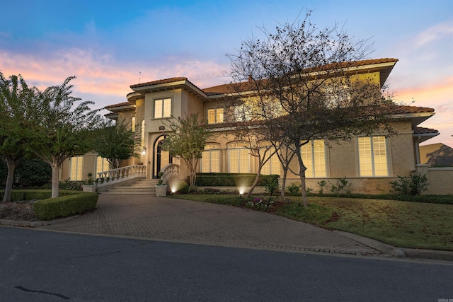 mediterranean / spanish home featuring a tiled roof, decorative driveway, and stucco siding