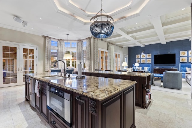 kitchen featuring oven, a sink, open floor plan, french doors, and a center island with sink