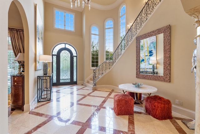 foyer entrance featuring arched walkways, baseboards, stairs, ornamental molding, and an inviting chandelier