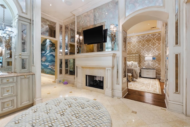 living area featuring wallpapered walls, a fireplace, arched walkways, and crown molding