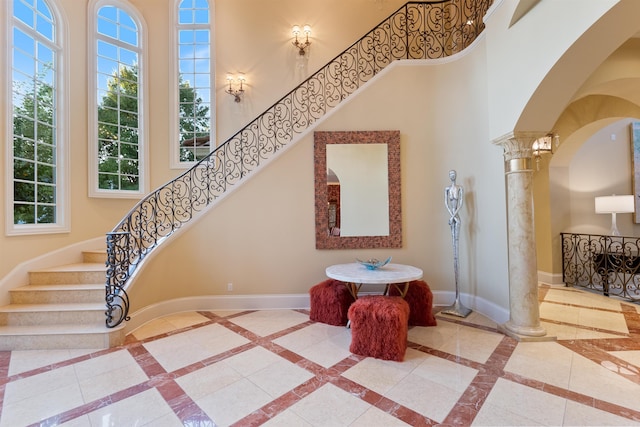 staircase with arched walkways, a high ceiling, decorative columns, and baseboards