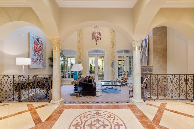 entrance foyer with french doors, crown molding, a towering ceiling, and ornate columns