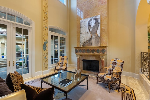 living room featuring a high end fireplace, french doors, a towering ceiling, and baseboards