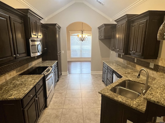 kitchen featuring arched walkways, light tile patterned floors, stainless steel appliances, ornamental molding, and a sink