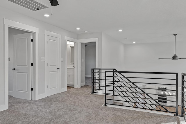 hallway featuring visible vents, baseboards, an upstairs landing, carpet floors, and recessed lighting