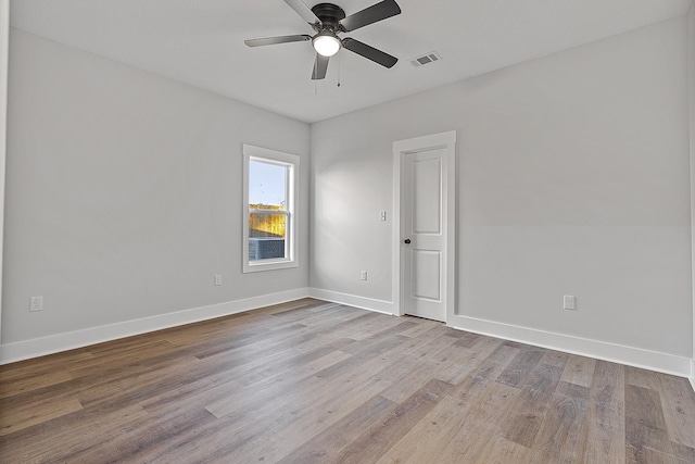 empty room with a ceiling fan, baseboards, visible vents, and wood finished floors