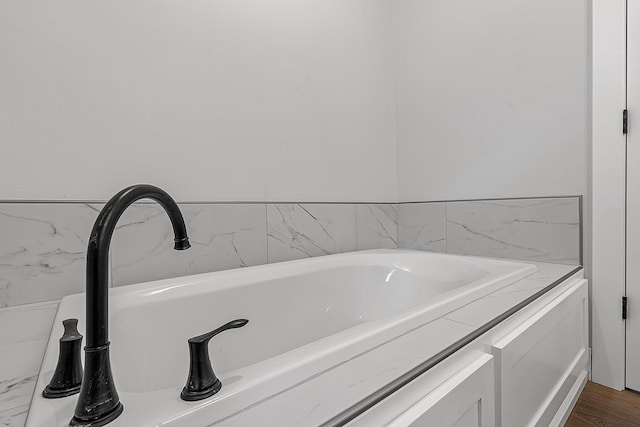 bathroom with a bathing tub, a sink, and wood finished floors