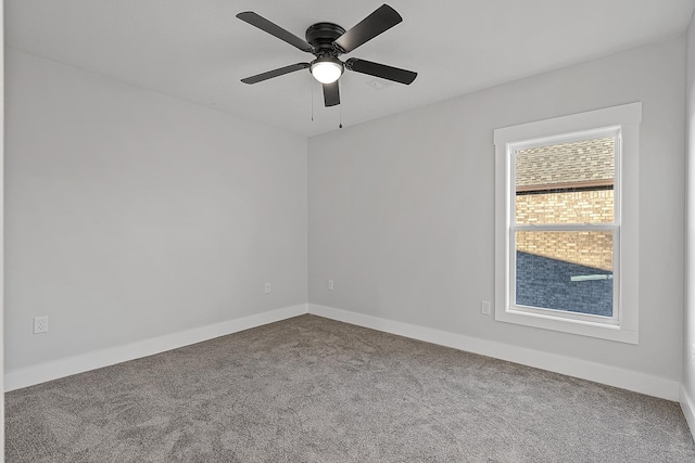 carpeted spare room featuring baseboards and a ceiling fan