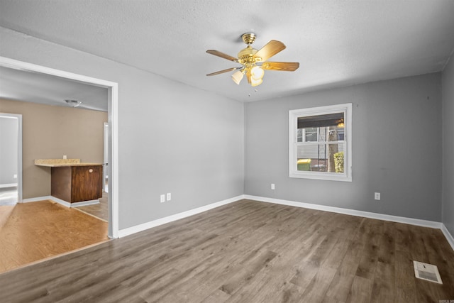 spare room featuring visible vents, baseboards, and wood finished floors