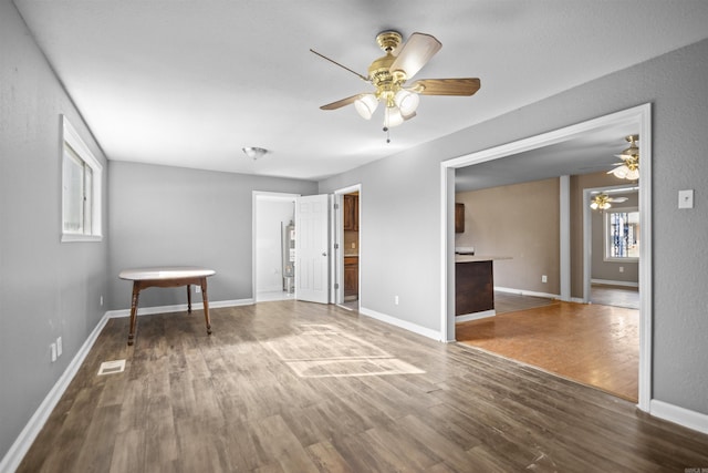 empty room featuring a ceiling fan, baseboards, and wood finished floors