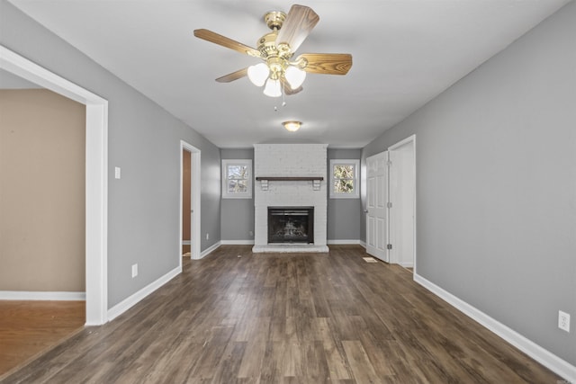 unfurnished living room featuring dark wood-style floors, a fireplace, baseboards, and a ceiling fan