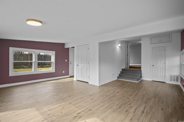 interior space with stairway, light wood-style flooring, visible vents, and baseboards