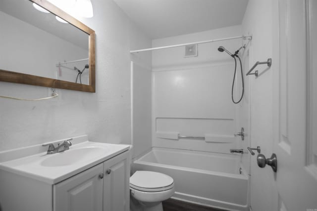 full bath featuring washtub / shower combination, a textured wall, vanity, and toilet