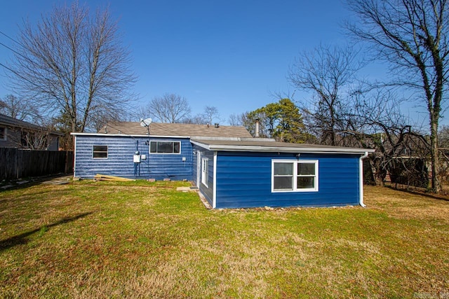 rear view of house with fence and a yard