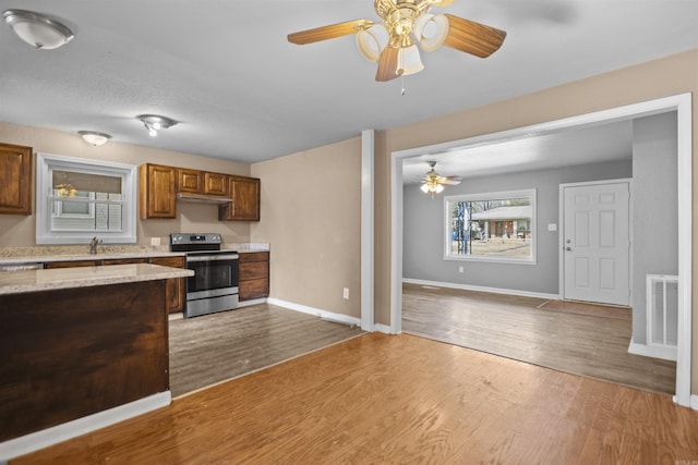 kitchen featuring baseboards, visible vents, electric stove, and wood finished floors