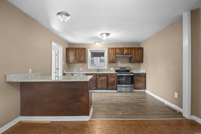 kitchen with a peninsula, electric range, a sink, wood finished floors, and baseboards