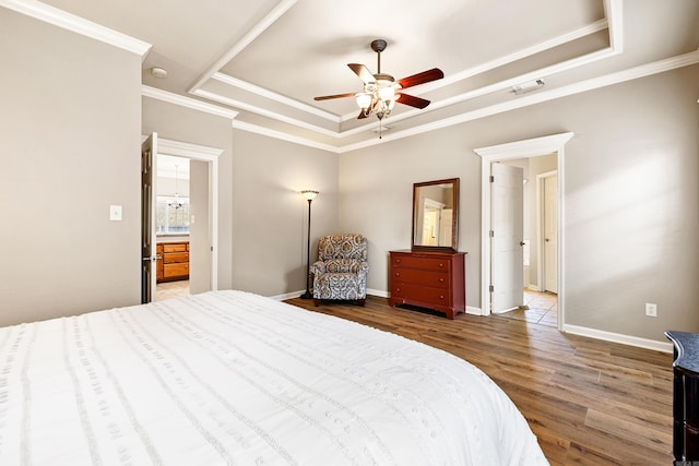 bedroom featuring baseboards, visible vents, ornamental molding, wood finished floors, and a tray ceiling