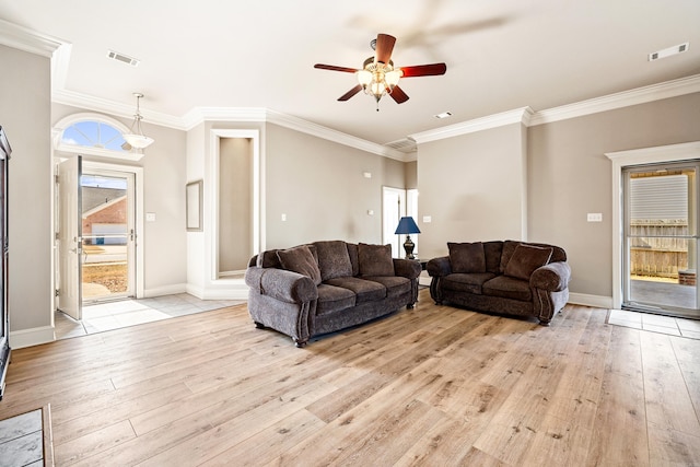 living area with light wood-style floors, visible vents, and ornamental molding