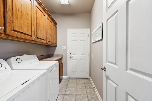 washroom featuring light tile patterned floors, washer and clothes dryer, cabinet space, and baseboards