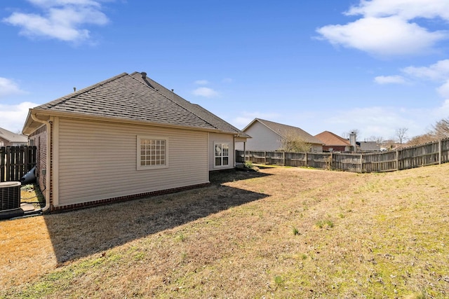 exterior space with a shingled roof, central air condition unit, fence, and a lawn