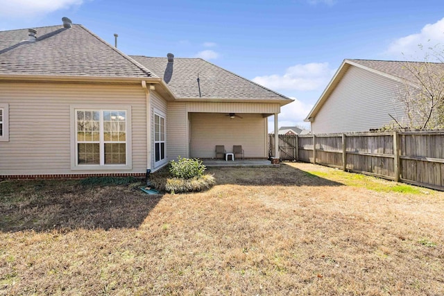 rear view of house with a shingled roof, fence, a ceiling fan, a yard, and a patio area