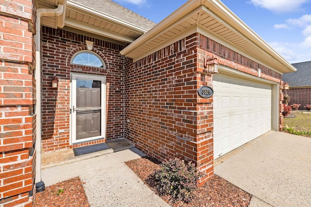 doorway to property featuring driveway, a shingled roof, and brick siding