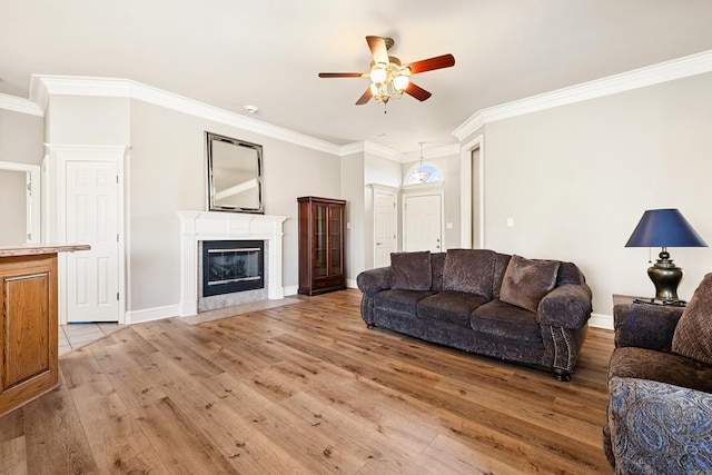 living room with ornamental molding, light wood-type flooring, a ceiling fan, and a premium fireplace