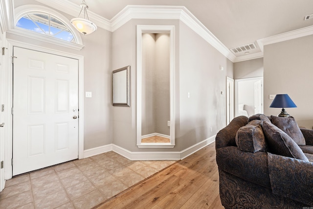 foyer entrance with baseboards, visible vents, and crown molding