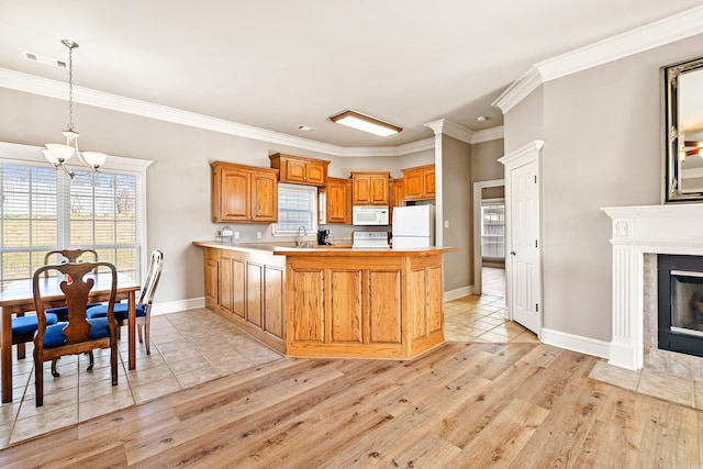 kitchen featuring visible vents, light wood-style floors, a tile fireplace, white appliances, and a peninsula