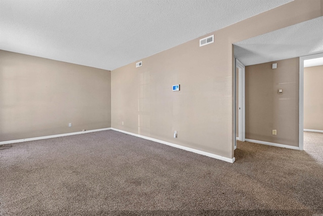 spare room featuring baseboards, visible vents, a textured ceiling, and carpet flooring