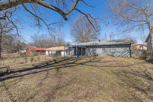 rear view of house featuring a lawn, fence, and a sunroom