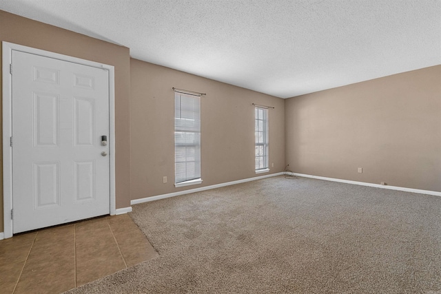 interior space featuring a textured ceiling, baseboards, and tile patterned floors