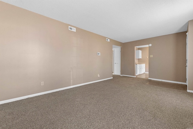 carpeted empty room featuring visible vents, a textured ceiling, and baseboards