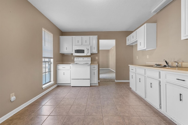 kitchen featuring white appliances, white cabinetry, a sink, and light tile patterned floors