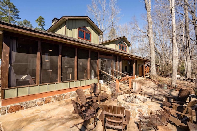 back of property featuring a sunroom, a chimney, a fire pit, and a patio