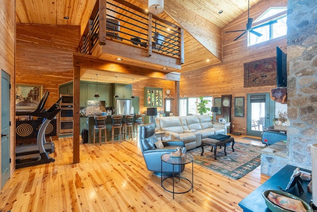 living room featuring light wood-type flooring, wood ceiling, wooden walls, and ceiling fan