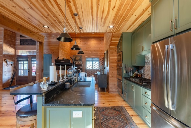 kitchen featuring wood walls, a sink, wood ceiling, appliances with stainless steel finishes, and green cabinetry