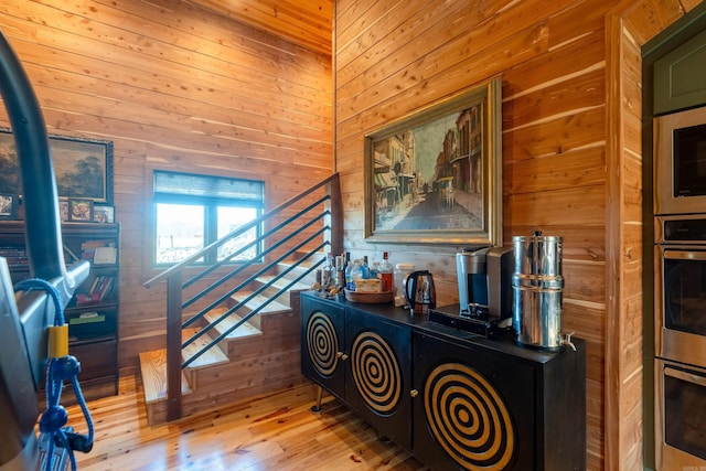 hallway featuring stairs, wood walls, and wood finished floors