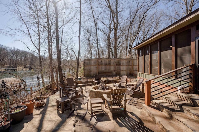 view of patio with a sunroom, fence, and a fire pit