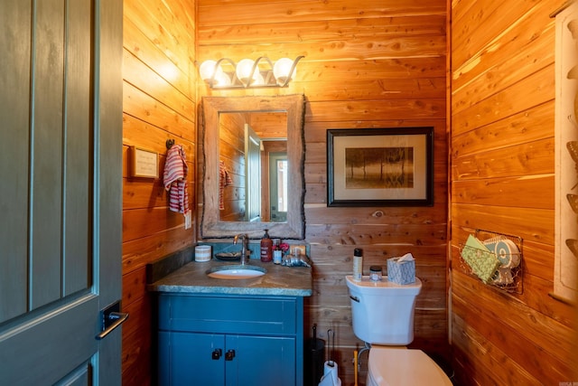 bathroom featuring wood walls, vanity, and toilet