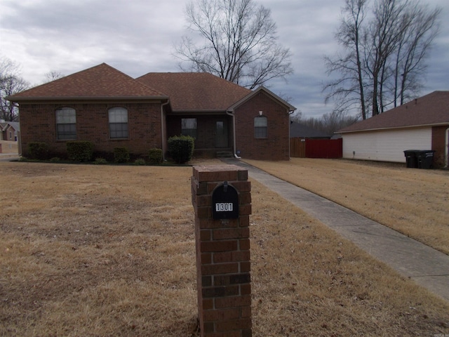 view of front of property with roof with shingles, a front lawn, and brick siding