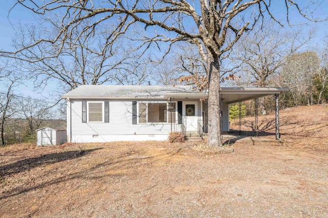 view of front facade with an outbuilding, an attached carport, a storage shed, driveway, and crawl space