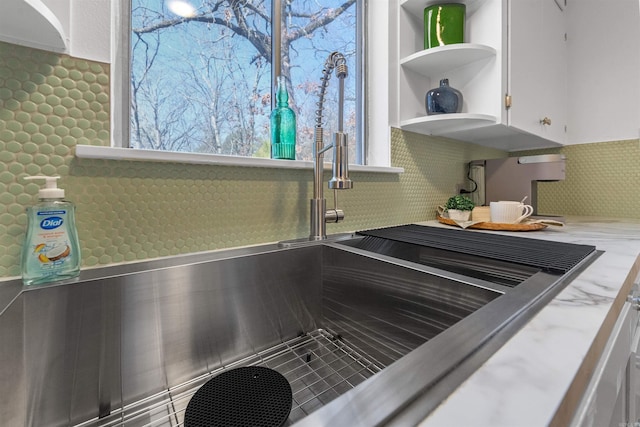 details with white cabinets, a sink, backsplash, and open shelves