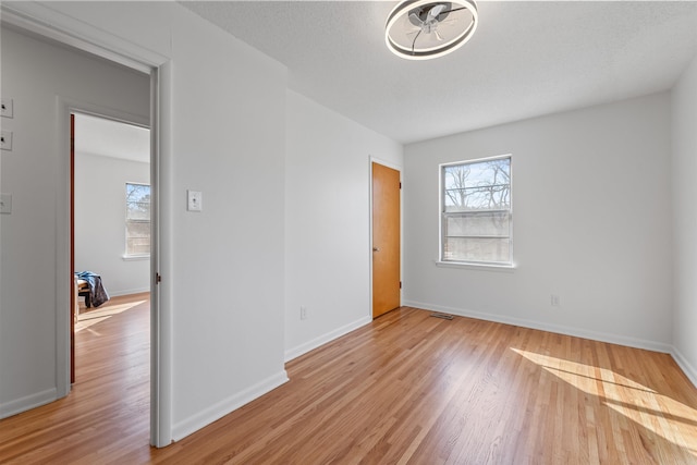 unfurnished room featuring light wood finished floors, plenty of natural light, and baseboards