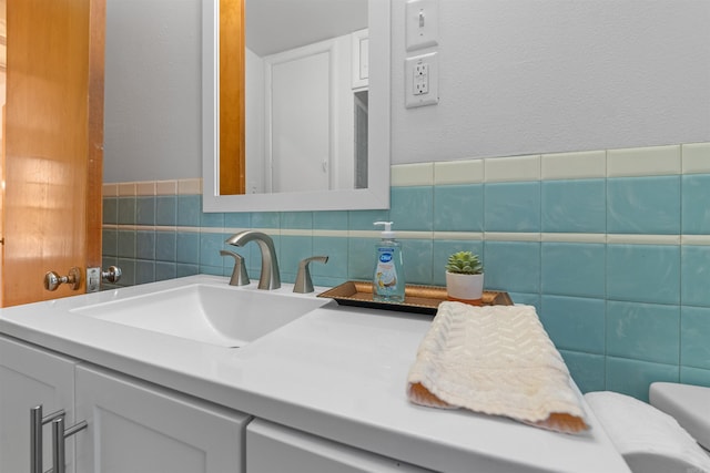 half bathroom featuring a textured wall, vanity, and toilet