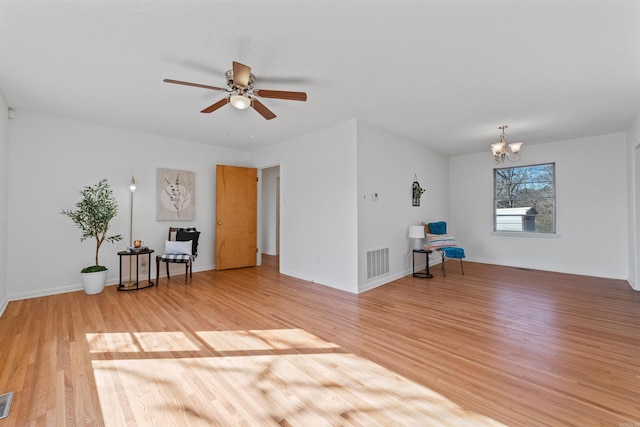 unfurnished room featuring ceiling fan with notable chandelier, visible vents, and light wood-style floors