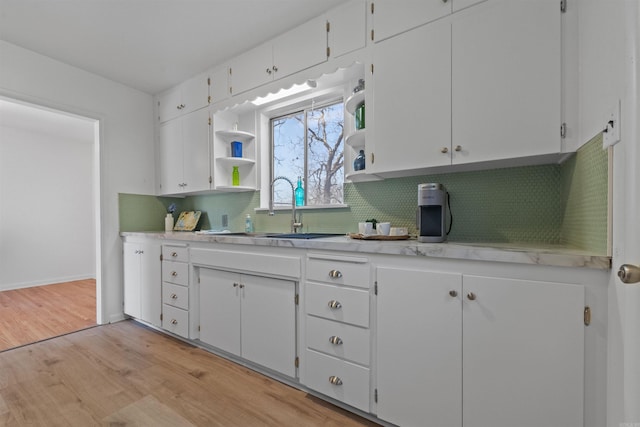 kitchen with tasteful backsplash, light countertops, a sink, and white cabinetry