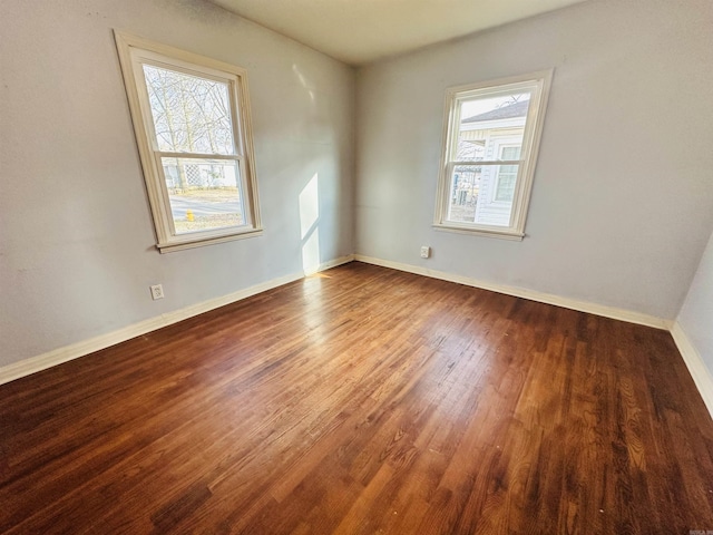 spare room with baseboards and wood finished floors