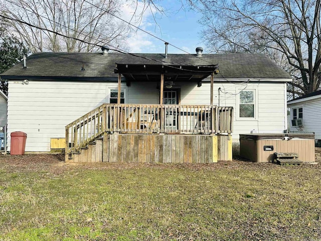 rear view of house featuring a hot tub, a deck, and a yard